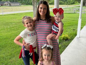 A smiling woman with 3 small children