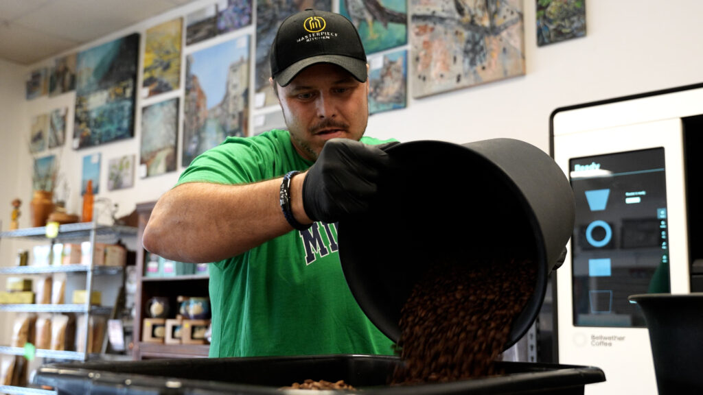 A man pouring coffee into a grinder